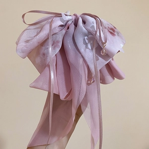 Dettaglio del fermaglio per capelli in chiffon rosa con motivi floreali e nappe di perle