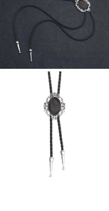 Detail of vintage bolo tie with oval metal slider and brown stone on braided leather cord
