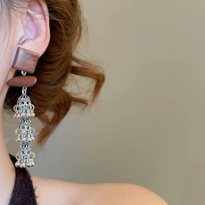 Gros plan de boucles d'oreilles ethniques avec carré en bois et cloches jhumka argentées