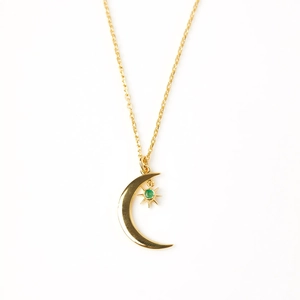 Detailed macro of S925 silver crescent moon necklace with green star gemstone in gold finish