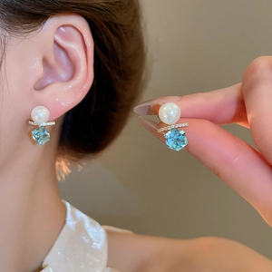 Close-up of square blue zircon earrings with pearls and 18k gold plating details