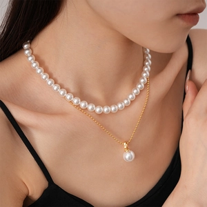 Detailed view of 2-piece layered pearl necklace set with golden beads on model neck
