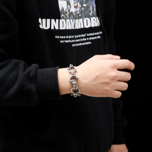 Macro shot of silver heavy-duty link bracelet with punk skull rings on model wrist