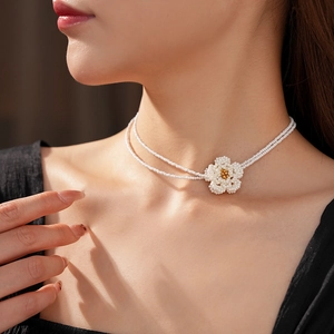 Close-up of a double-layered white pearl camellia necklace with gold bead accents