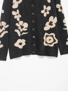 Details einer Strickjacke mit Blumen-Jacquard, dunklen Knöpfen und Rippbündchen