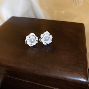 Detailed macro view of camellia flower earrings with white petals and pearls on wood