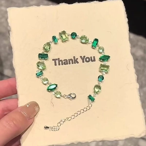 Detailed view of multi-shaped green zircon gemstones on adjustable silver link bracelet