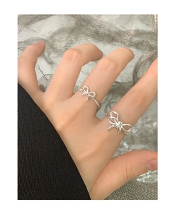 Detail view of two stacked S925 sterling silver bow rings with elegant twisted design