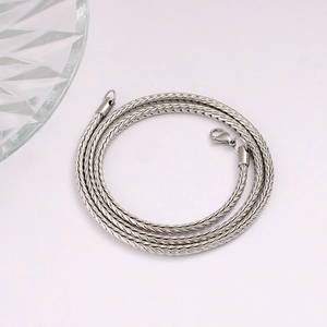 Detailed macro view of silver foxtail chain showing woven stainless steel and lobster clasp