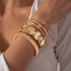Detail of gold-plated geometric bracelet set featuring hammered and woven textures