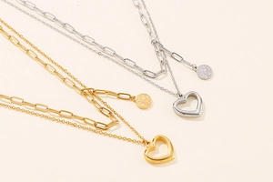 Detail of gold and silver layered necklaces with heart and coin charms on link chains