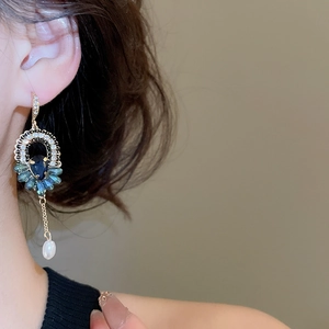Détail de boucles d'oreilles rétro avec cristal bleu, marquises et perle suspendue