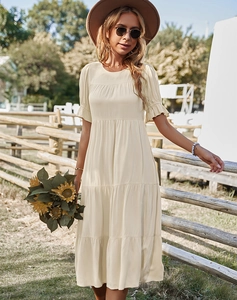 Détail d'une robe beige à manches courtes avec volants superposés dans un cadre naturel extérieur