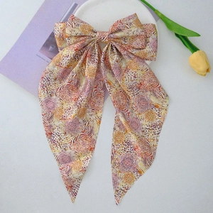 Detail of large leopard print bow hair clip with ribbons on a decorative plate
