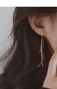Detail of elegant gold tassel earrings featuring cascading geometric long chain fringe