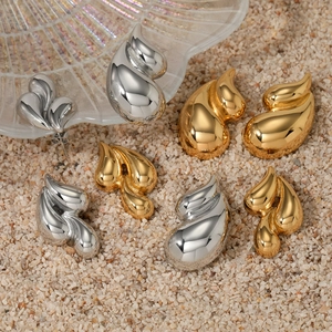 Modern geometric teardrop earrings in gold and silver finish on a warm sandy background
