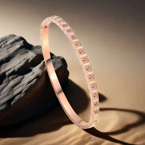 Macro detail of rose gold stainless steel bangle with square-set cubic zirconia accents