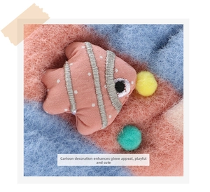Detail of pink embroidered fish and soft pom-poms on plush knit children's winter gloves