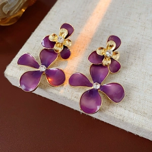 Detailed macro view of purple flower earrings with gold edges and crystal centers