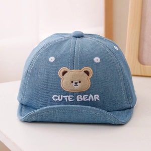 Détail de la casquette bébé en denim avec broderie ours et œillets blancs