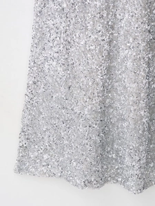 Gros plan sur les paillettes argentées et les coutures détaillées d'une robe de soirée