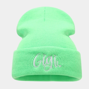 Close-up of the neon green ribbed knit beanie featuring detailed Gigi embroidery