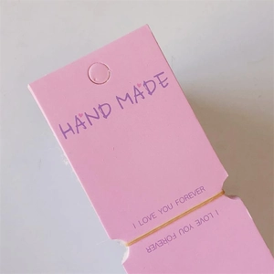 Detailed view of pink handmade paper display tags with purple typography and hanging holes