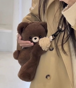 Detailed view of plush brown teddy bear backpack with soft fabric and black shoulder strap