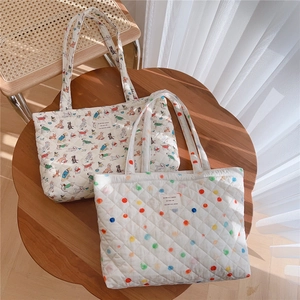 Close-up of quilted tote bags featuring polka dot and cartoon dog patterns on wood table