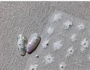 Detailed view of 3D white floral nail stickers with pearls and lucky flower patterns