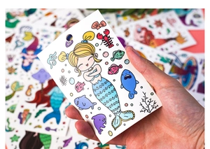 Detailed view of hand holding a colorful mermaid coloring card with cute ocean patterns