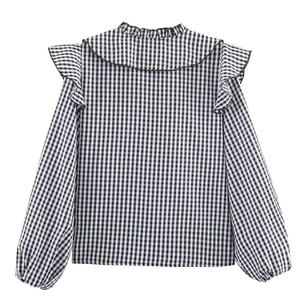 Detailed back view of black and white plaid blouse with ruffled shoulders and elastic cuffs