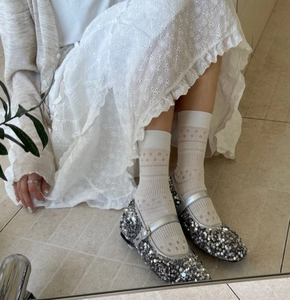 Close-up of silver sequin Mary Jane flats paired with white hollow lace floral socks