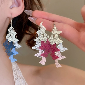 Detail of gradient painted butterfly tassel earrings in blue and pink on model