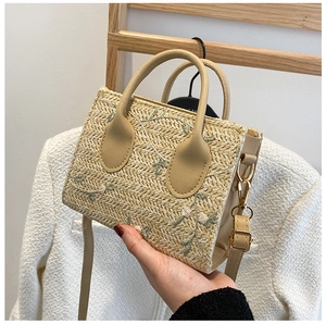Detail of straw woven bag featuring exquisite floral embroidery and PU leather handle