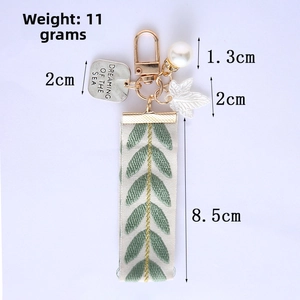 Detailed size view of floral strap keychain with pearl, leaf charm and metal tag