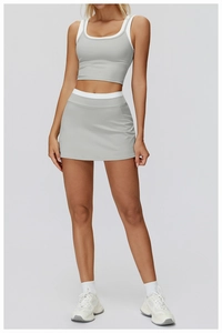 Detail view of light grey two-piece yoga set with white contrast trim and pleated skort