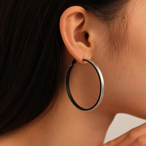 Close-up of large hoop earring featuring textured silver exterior and black inner lining