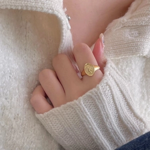 Close-up of a vintage golden coin signet ring featuring a detailed embossed portrait