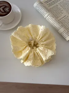 Close-up of cream yellow lace embroidery scrunchie with delicate floral scalloped edges