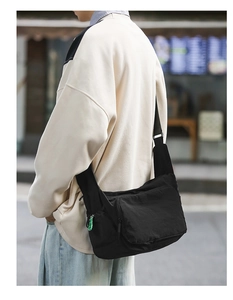 Detail of black nylon messenger bag featuring a distinctive green zipper pull accent