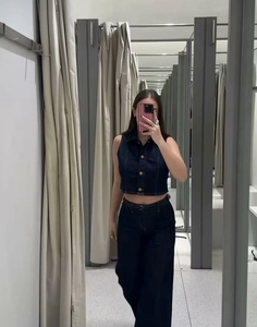 Détail d'un ensemble en jean bleu foncé avec crop top sans manches et pantalon ceinturé
