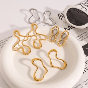 Minimalist irregular wavy titanium steel earrings in gold and silver finish on a plate