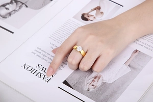 Detail of 6mm round zircon engagement ring in gold finish on a fashion magazine background