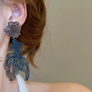 Detail of blue hollow koi fish drop earrings with grey resin flower stud on model