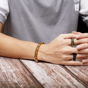Close-up of golden Byzantine chain bracelet and black gold rings on a model's hand