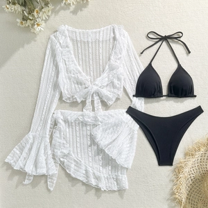 Flat lay of four-piece bikini set with black rib fabric and white floral lace cover-up