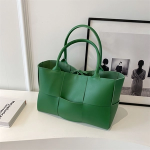 Detail of green woven tote bag showing luxury synthetic leather texture and craftsmanship