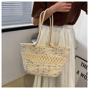 Close-up of woven straw tote bag featuring detailed wave texture and durable handles