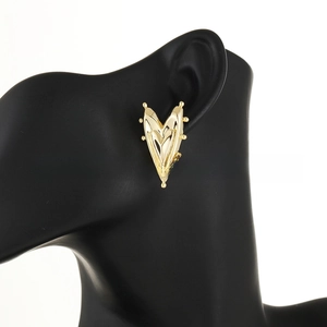 Macro side view of gold-plated V-shaped heart earrings with studded bead detailing